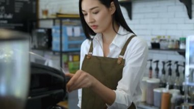 Kahve dükkanı konsepti. Kadın personel kahve makinesinin hortumunu temizliyor. 4k Çözünürlüğü.