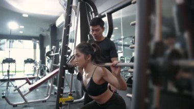 Fitness konsepti. Bir antrenör sporculara spor salonunda çömelme hareketleri öğretiyor. 4k Çözünürlüğü.