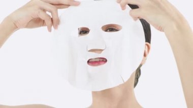 Güzellik konsepti. Beyaz arka planda maske takan genç bir Asyalı kadın. 4k Çözünürlüğü.