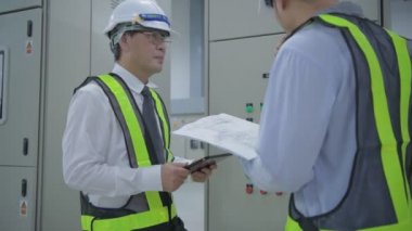 Mühendis konsepti. Teknisyen takım liderini bir iletişim cihazıyla koordine ediyor. 4k Çözünürlüğü.