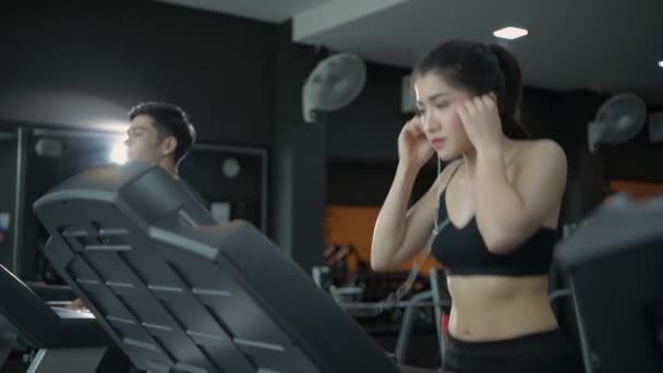 フィットネスコンセプト トレッドミルを走り ジムで音楽を聴く若いアジアの女性 4K分解能 — ストック動画