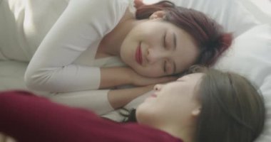 4k Çözünürlük ev arkadaşı konsepti. Asyalı kadınlar yatak odasında yan yana yatıyorlar..