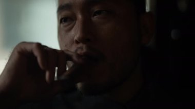 Gece kulübü konsepti 4k Kararlılık. Restoranda puro içen Asyalı bir adam. Alkollü içecekler satan bir grup özel kulüp..