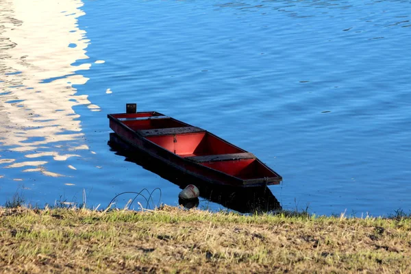 黑暗的木河船与红色中心栓与河岸漂浮在平静清澈的蓝色水面上 在温暖的阳光明媚的日子在日落 — 图库照片
