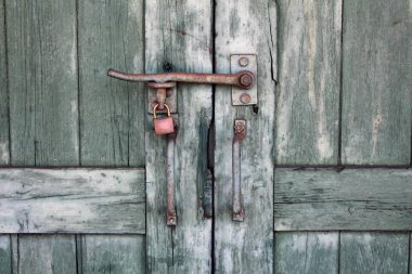 İki paslı metal kolları ve küçük asma kilit ile kilitli güçlü mandallı rustik eski yeşil ahşap kapılar çekim