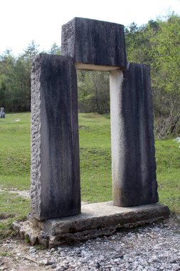 Glagolitic letter made from stone called Uspon Istarskog razvoda scattered over large grass area and surrounded with trees