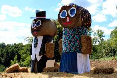 Geleneksel giysiler giymiş mutlu yaşlı erkek ve kadın heykel tamamen bulutlu yaz gününde saman yapılmış