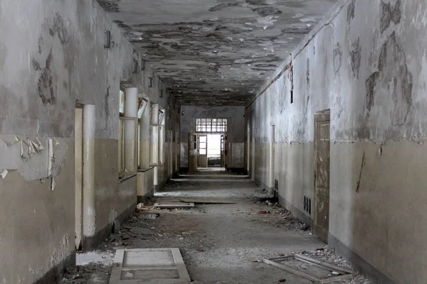 Abandoned building dilapidated corridor with broken doors, windows, glass, wires, bricks and rubble on the floor