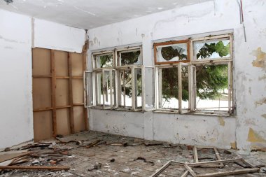 Kırık pencereli, imha edilmiş döşeme panoları ve harap duvar yalıtımı ile terkedilmiş binada Oda
