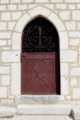 Velencei stílusú fém bejárati ajtók erős zsanérok és csiszolt ajtókárs szerelt hagyományos kőfal kő lépések előtt a meleg napsütéses napon