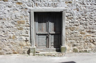 Masif çerçeve ile taş duvara zincir ve asma kilit ile kilitli rustik gri ahşap kapılar