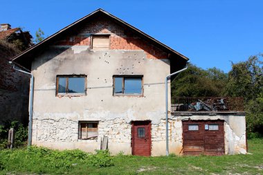 Bağlı garaj ile banliyö aile tuğla ev ve sıcak güneşli gün arka planda kesilmemiş çim ve orman bitki örtüsü ile çevrili kapladığı pencerelerin ve ağır kilitli kapılar ile savaş sırasında shrapnels ve mermi kırık hasarlı cephe
