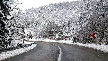 Her iki tarafta taze kar ile kaplı daha iyi çekiş ve ağaçlar ve bitki örtüsü için asfalt serpilir kum ile temizlenmiş kış yolu