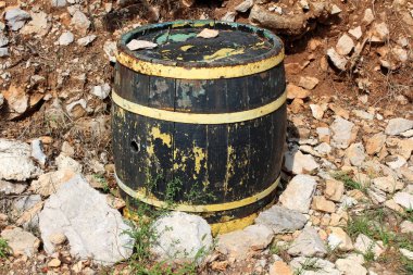 Kırık panoları ve soluk renk ile ahşap asma varil sıcak güneşli gün taşlar ve toprak ile çevrili arka bahçesinde sol