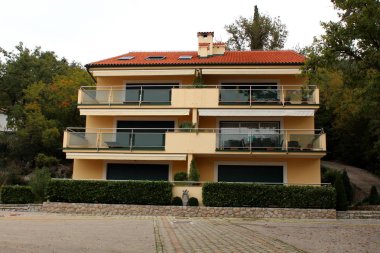 Dört daire, cam balkon, hedge ve taş fayans ön ve ağaçların çevreleyen bahçesinde kaplı Akdeniz Villa