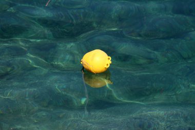 Sarı plastik görünür kayalar ve bağlı halat sıcak güneşli gün alt bağlı sakin açık denizde yüzen şamandıra