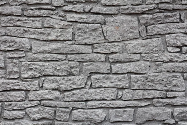 Dark grey stone wall texture made from various large and small stones