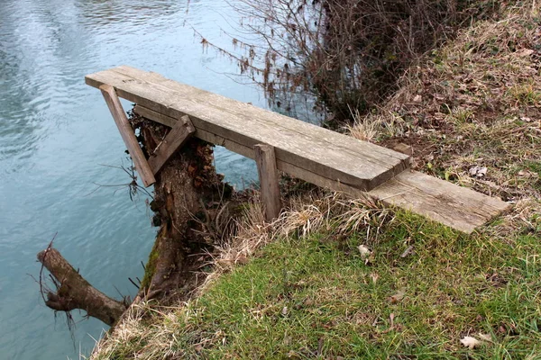 自家製の川のダイビングボードは 未カットの草や落ち葉で覆われた川の土手の木の切り株に取り付けられる板から作られる — ストック写真