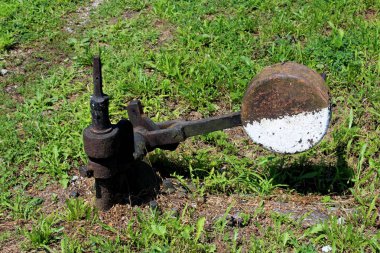 Ahşap tahta üzerinde büyük vidalar ile monte kolu ile paslanmış siyah ve beyaz metal demiryolu anahtarı mekanizması tamamen sıcak güneşli günde büyümüş kesilmemiş yeşil çim ile çevrilidir