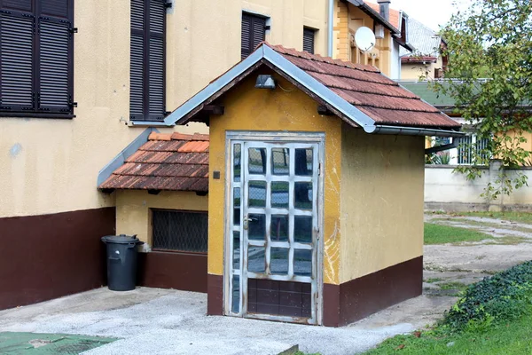 Unusual glass door family house basement entrance removed from main building and made to look like small house structure connected with tunnel surrounded with concrete and grass on warm sunny day