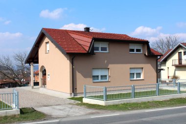 Modern tasarım ile yeni banliyö aile evi gri metal çit ile çevrili, çim alanı ve kum kaplı arka bahçesinde döşeli yolun yanında