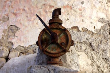 Taş duvarın önünde Şehir meydanlarında kurulmuş el pompaları için eski ve tamamen paslanmış geleneksel su valfi