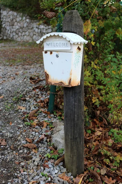 Rostiger Weißer Briefkasten Mit Willkommensschild Auf Altem Holzmast Neben Geschottertem — Stockfoto