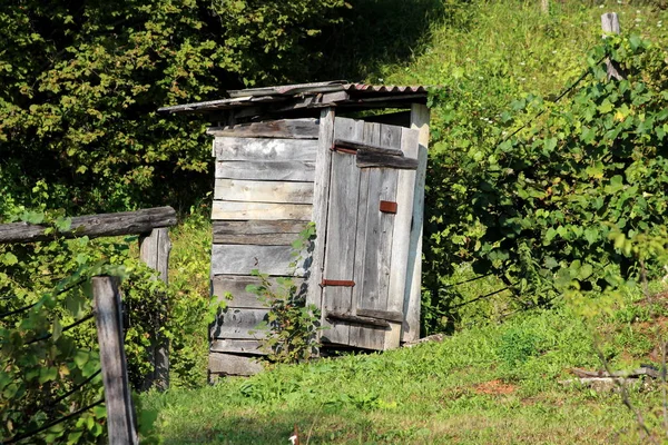 Tradiční Dřevěná Toaleta Opírá Jednu Stranu Rozbitými Prkny Obklopenou Trávou — Stock fotografie