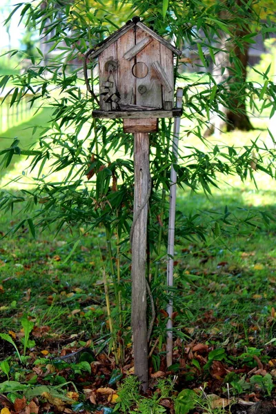 古老的老式木鸟屋坐落在木钉的顶部 由放置在后院的金属棒支撑 周围是绿草和植物 — 图库照片