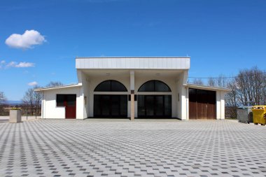 Arka planda mavi gökyüzü ile yaprakları olmadan modern taş fayans ve ağaçlar ile çevrili iki oda ve depolama alanı ile yenilenmiş mezarlık morga Binası