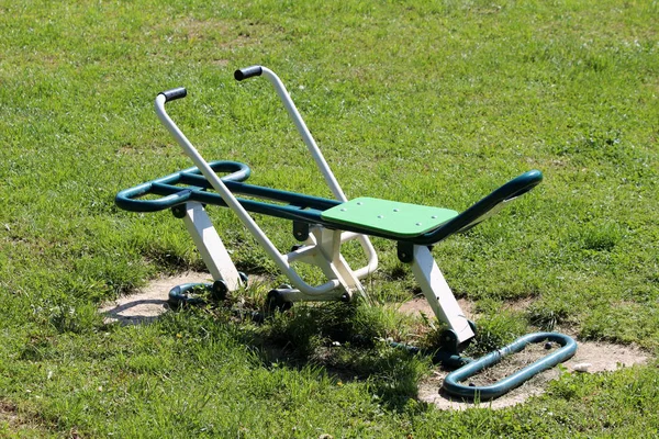 暖かい晴れた春の日にノーカットの草に囲まれた屋外の公共公園は 新鮮に塗装された運動器具 — ストック写真