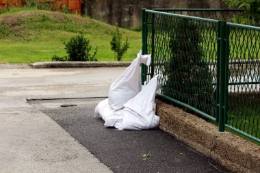 Sokağın köşesinde kum dolu beyaz kum torbaları daha sonra yağmurlu bahar günlerinde sel koruması olarak kullanılmak üzere koyu yeşil metal çitlerin yanına bırakıldı.