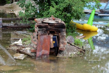 Kırmızı tuğla arka bahçe barbekü tamamen çamurlu sel suyu ve yağmurlu bahar gününde kırık şeyler ile çevrili doğal afet sırasında tahrip