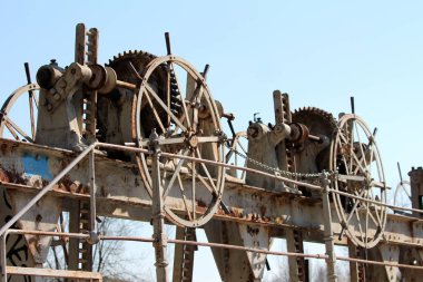 Açık mavi gökyüzü arka planda izinsiz kullanımı önlemek için küçük zincirile kilitlenmiş terk edilmiş barajçeşitli boyutu cogwheel paslı dişliler