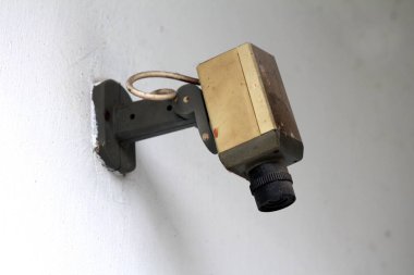 Vintage retro küçük siyah beyaz güvenlik kamerası bina duvarına monte edilmiş ve sıcak bahar gününde toz kalın tabaka ile kaplı