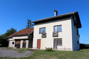 Ekli garaj ve açık depolama binası ile terk edilmiş aile evi çim ve açık mavi gökyüzü arka plan üzerinde döşenmiş driveway çevrili