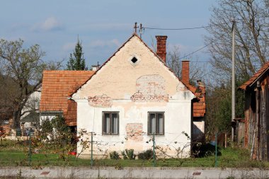 Terk edilmiş eski kırmızı tuğlalar çatlak cepheli banliyö aile evi ve diğer binalar ve ahşap ahır ile çevrili iki harap ahşap çerçeve penceresi.