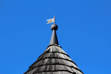 Terk edilmiş eski banliyö aile evinin çatısında açık mavi arka planda ahşap tahta fayanslarla kaplı sivri bayrak şeklinde açık gri metal antika rüzgar gülü enstrüman.