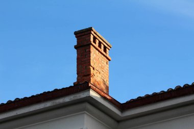 Eski eğik kırmızı tuğlalı baca terk edilmiş ofis binasının çatısına monte edilmiş üç açıklık açık mavi gökyüzü arkaplanı.