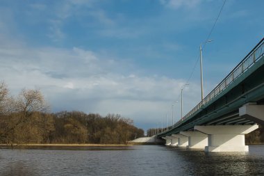 Geniş nehir, arka plan için mavi gökyüzü üzerinde uzun beton köprü. Alt görünümü