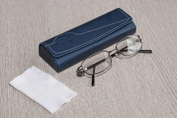 Glasses, case and handkerchief for cleaning glasses on grey wooden table