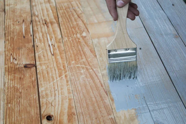 Peindre le vieux plancher en bois avec un pinceau gris. contexte Image En Vente