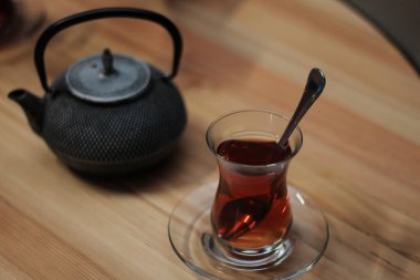 siyah çay kaşık ve karanlık bir arka plan üzerinde ahşap masa üzerinde su ısıtıcısı ile bardak