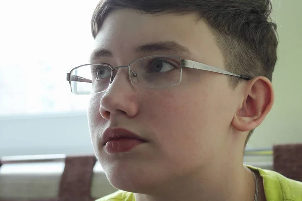 pensive teen with glasses looking up. serious look
