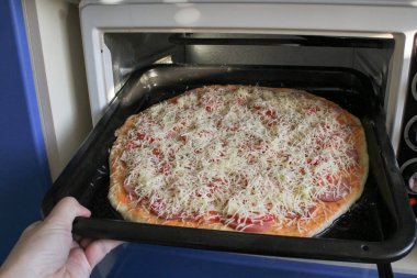 Pizza ile fırın tepsisine fırına koyarak kadın. Peynir ve sosis pizza.