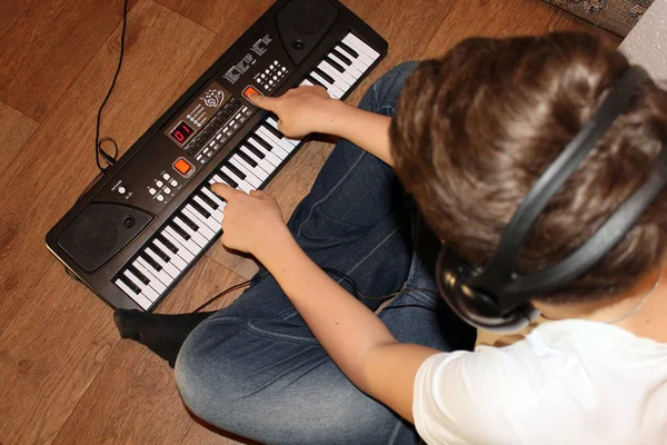 Closeup of a focused teen playing on the keyboard on the floor
