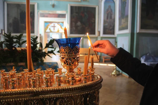 man in the temple praying, lights and puts a candle.