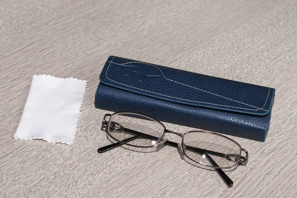 Glasses, case and handkerchief for cleaning glasses on grey wooden table