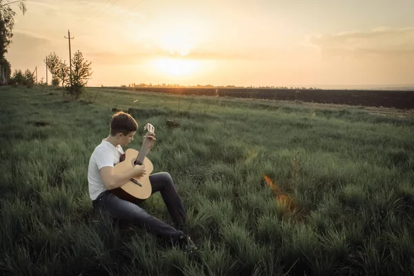 Adolescente jugando guitarra al aire libre en el verano en el fondo de los árboles de abedul . —  Fotos de Stock