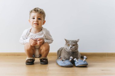 cute little boy and grey british shorthair cat in sleepers at home clipart